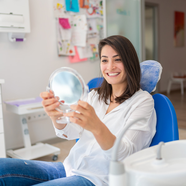 Girl checking her teeth after dental treatment